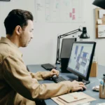 Designer 3D au travail sur ordinateur de bureau, affichant un modèle de meuble en cours de conception